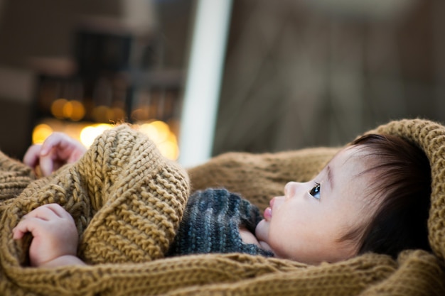 Het is de zijkant van een baby die een bruine deken draagt.