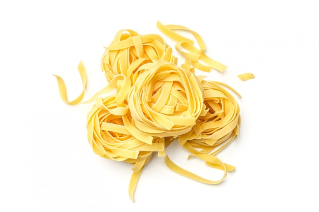 Het Italiaanse nest van deegwarenfettuccine dat op witte achtergrond wordt geïsoleerd