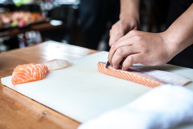 Het Japanse chef-kok kokende voedsel sneed zalmvis op het Hakbord