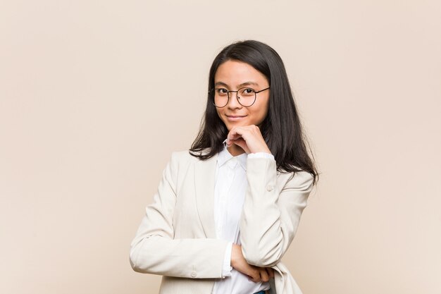 Het jonge bedrijfs chinese vrouw glimlachen gelukkig en zeker, wat betreft kin met hand.