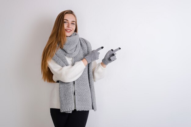 Het jonge, blonde meisje in handschoenen en sjaal toont op de lege muur, exemplaarruimte