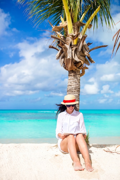 Foto het jonge boek van de vrouwenlezing tijdens tropisch wit strand