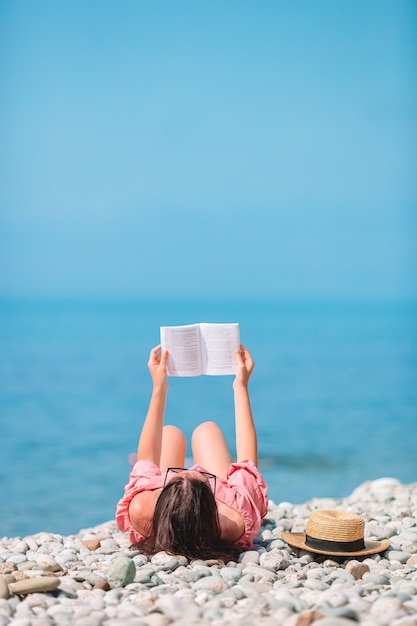 Het jonge boek van de vrouwenlezing tijdens tropisch wit strand