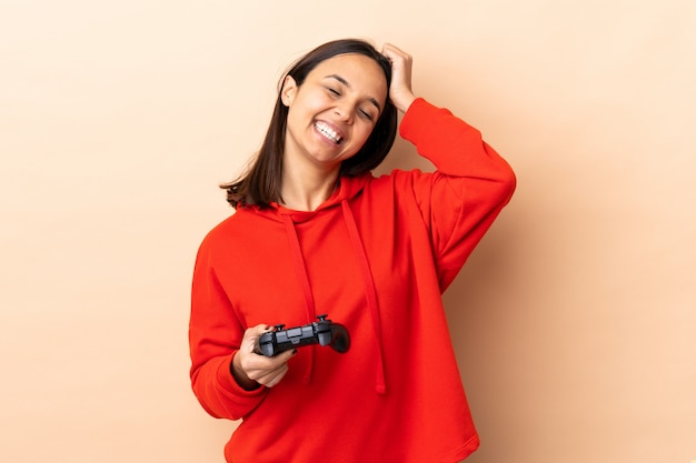 Het jonge brunette gemengde rasvrouw spelen met een videospellingscontrolemechanisme over het geïsoleerde lachen