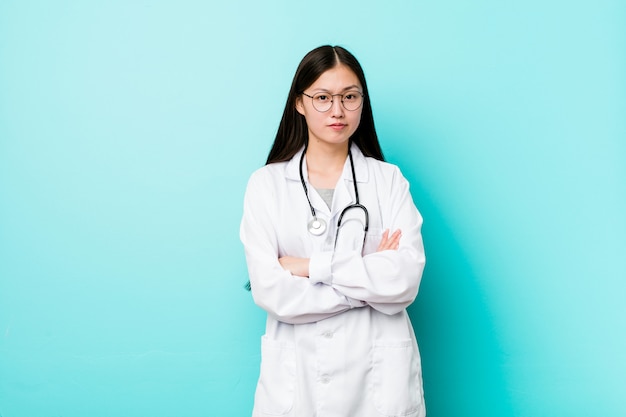 Het jonge Chinese artsenvrouw ongelukkige kijken in camera met sarcastische uitdrukking.