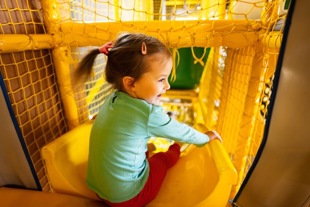 Het jonge geitjedia van het babymeisje bij geel speelplaatspark Kind in actief vermaak