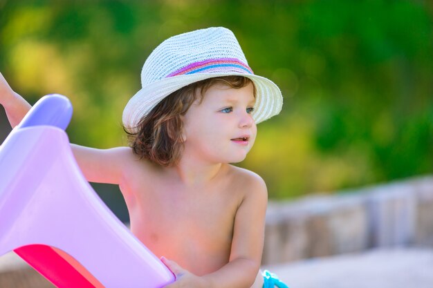 Het jonge geitjemeisje van de baby met hoed in de zomer op groen gebied