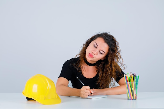 Het jonge ingenieursmeisje schrijft tekst op witte achtergrond