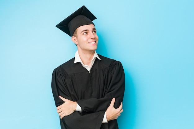 Het jonge Kaukasische gediplomeerde mens glimlachen zeker met gekruiste wapens.