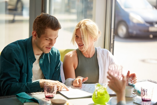 Het jonge Kaukasische paar kiest samen maaltijd in menu