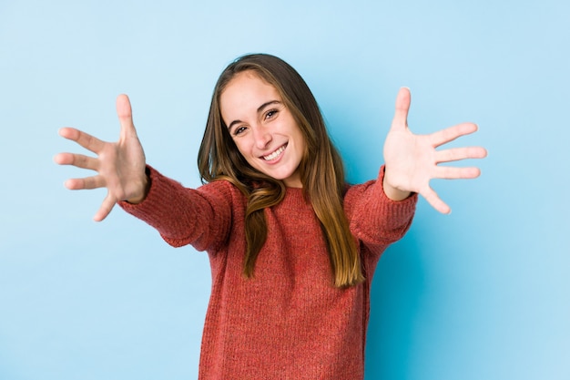 Het jonge Kaukasische vrouw geïsoleerd stellen voelt zeker het geven van een omhelzing aan de camera.