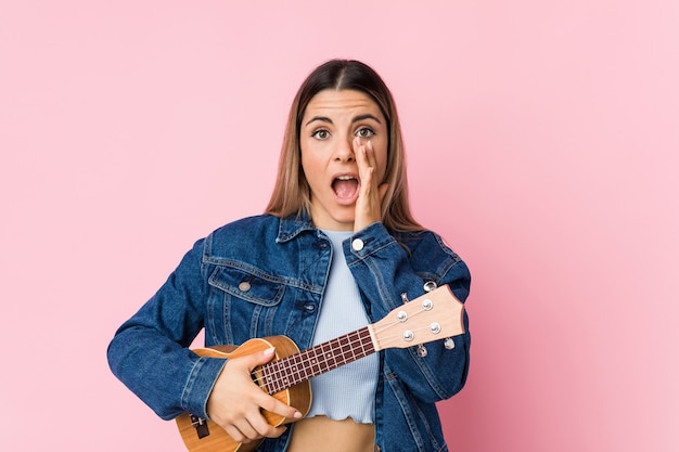 Het jonge Kaukasische vrouw spelen ukelele schreeuwen opgewekt aan voorzijde.