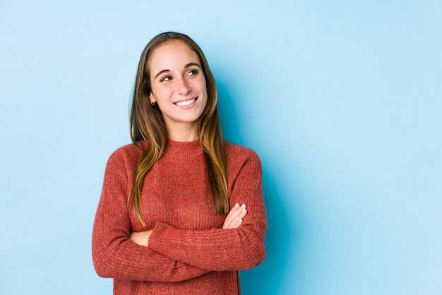 Het jonge Kaukasische vrouw stellen geïsoleerde glimlachen zeker met gekruiste wapens.