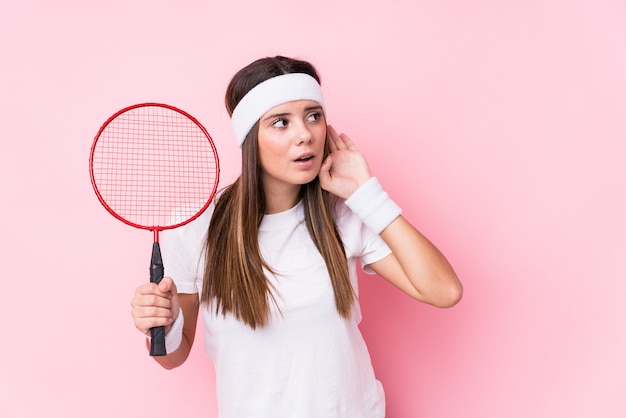 Het jonge Kaukasische vrouwen speelbadminton isoleerde het proberen aan het luisteren van een roddel.