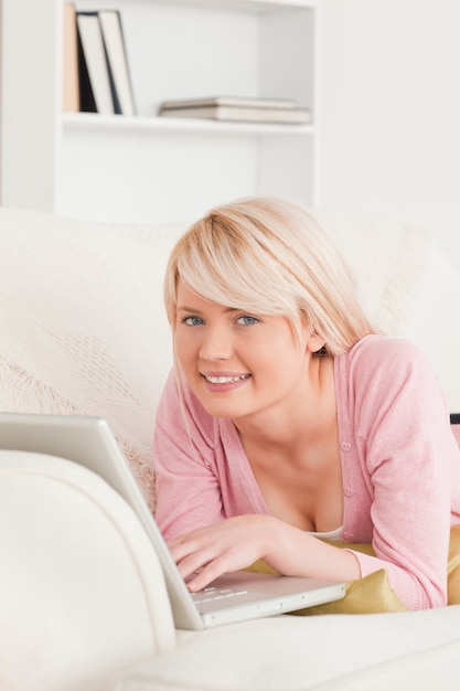 Het jonge knappe vrouw ontspannen met laptop terwijl het liggen op een bank