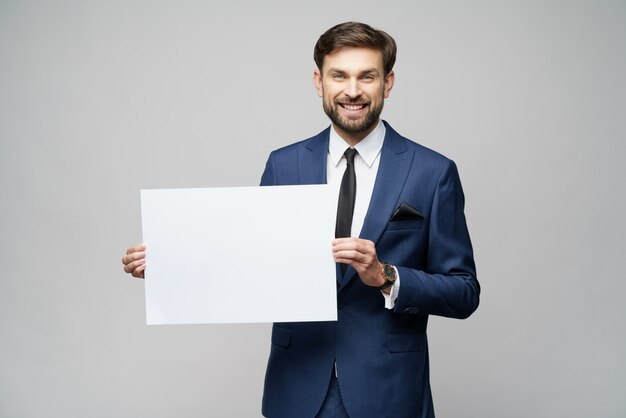 Het jonge lege teken van de zakenmanholding over grijze muur