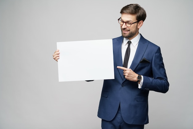 Het jonge lege teken van de zakenmanholding over grijze muur