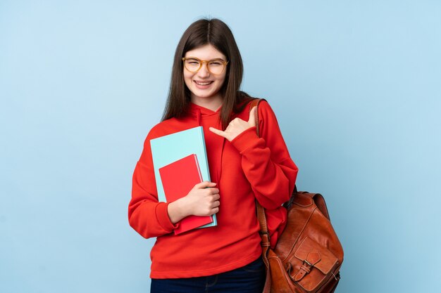 Het jonge meisje dat van de tienerstudent een salade over blauwe muur houdt die telefoongebaar maakt