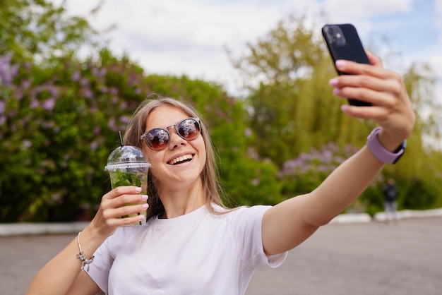 Het jonge meisje drinkt een verfrissende cocktailclose-up tegen de hemel