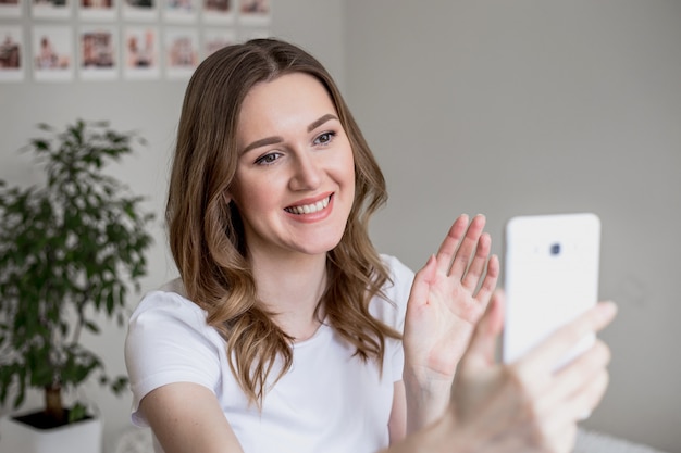 Het jonge meisje gebruikt een mobiele telefoon voor videochat tijdens quarantaine