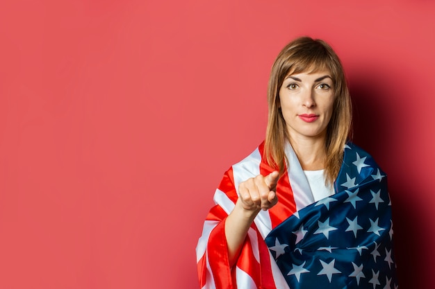 Het jonge meisje houdt de Amerikaanse vlag op een roze achtergrond.