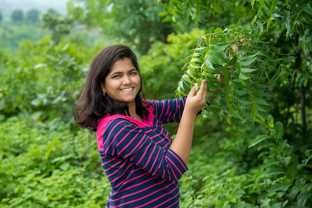 Het jonge meisje onderzoekt of neemt Neem (Azadirachta indica) Boomblad waar bij gebied