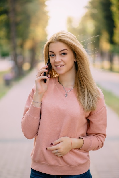 Het jonge meisje spreekt op telefoon openlucht