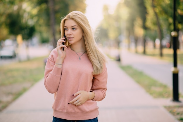 Het jonge meisje spreekt op telefoon openlucht