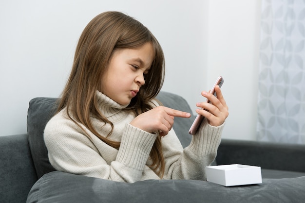 Het jonge meisje toont een wijsvinger in een smartphone.