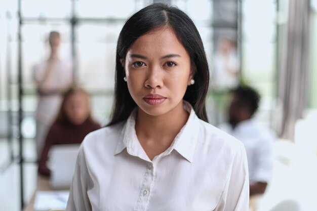 Het jonge mooie Aziatische portret van de bedrijfsvrouwenadviseur van een werknemer die de camera bekijkt