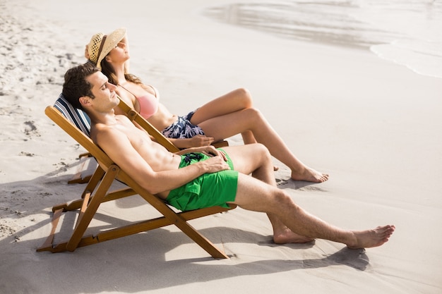 Het jonge paar ontspannen op leunstoel op het strand