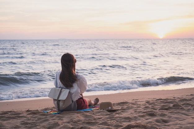 Het jonge reizigersvrouw ontspannen op tropisch strand bij zonsondergang