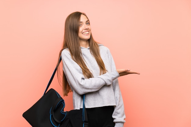 Het jonge roze van de sportvrouw uitbreidende handen aan de kant voor het uitnodigen om te komen