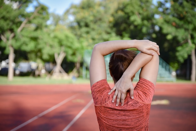 Het jonge sportenvrouw uitrekken zich op stadionspoor alvorens te lopen.