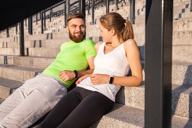 Het jonge sportieve paar rust en controleert samen hun fitnesshorloge. sport- en technologieconcepten.