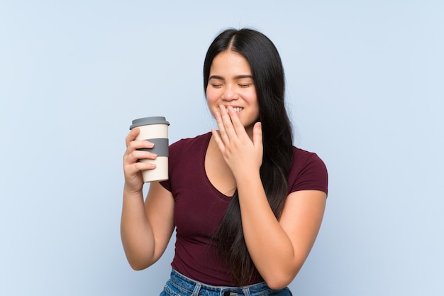 Het jonge tiener Aziatische meisje houdt haalt koffie weg glimlachend