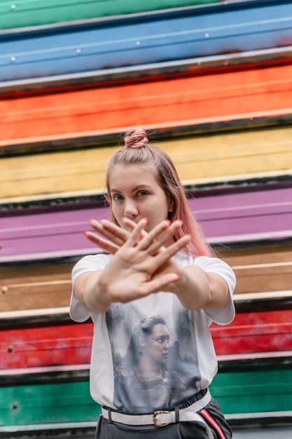 Het jonge tiener hipster meisje met roze haar toont stopteken met handen.