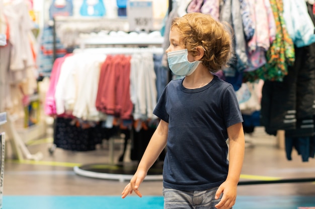 Het kind draagt een beschermend masker in de winkel. Veiligheid, bescherming van de gezondheid tijdens COVID-19 quarantaine.