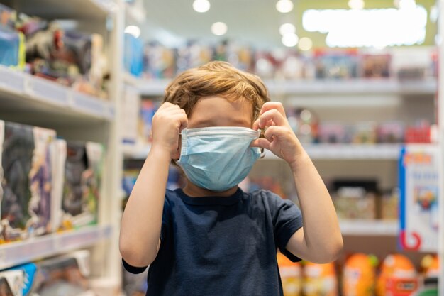 Het kind draagt een beschermend masker in de winkel. Veiligheid, bescherming van de gezondheid tijdens COVID-19 quarantaine.