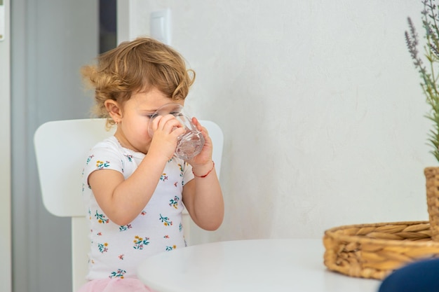 Het kind drinkt water uit een glas selectieve focus