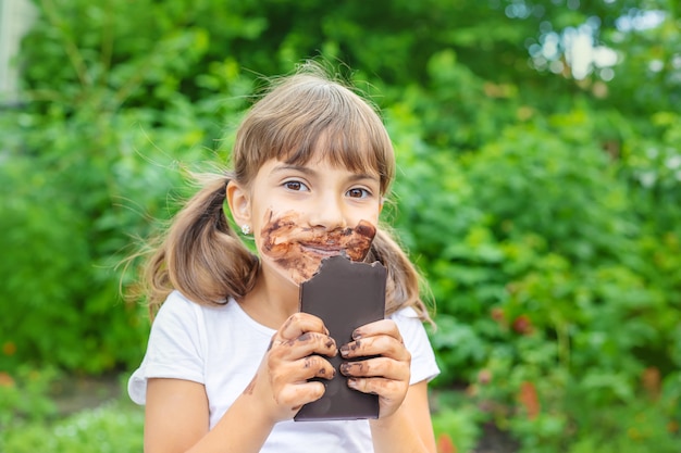 Het kind eet een chocoladereep.