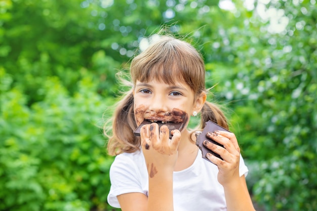 Het kind eet een chocoladereep.