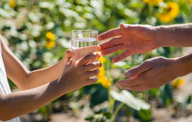 Het kind en de vader drinken en geven water in een glas. Selectieve aandacht.