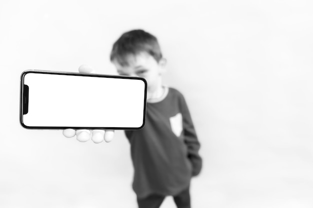 Het kind houdt de telefoon in zijn hand voor reclame op een gele achtergrondkleur