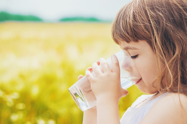 Het kind houdt een glas water in zijn handen. selectieve aandacht.