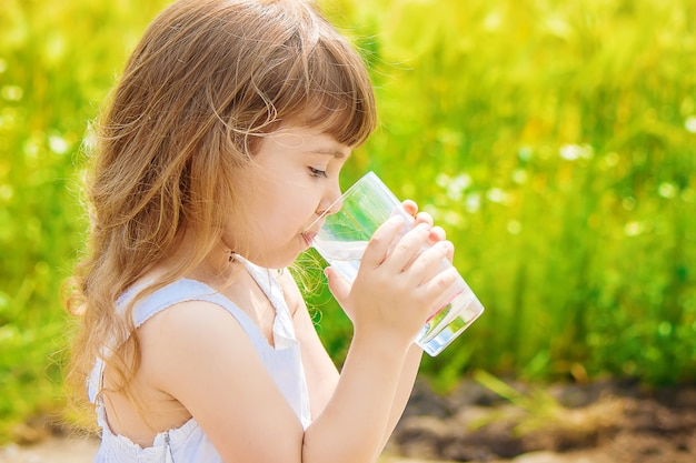 Het kind houdt een glas water in zijn handen. selectieve aandacht.