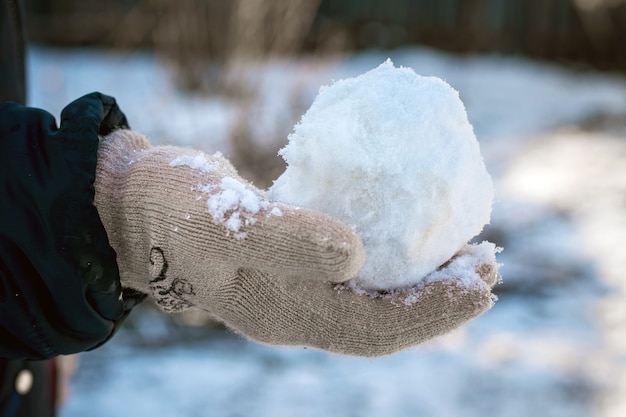 Het kind houdt een sneeuwbal in zijn hand