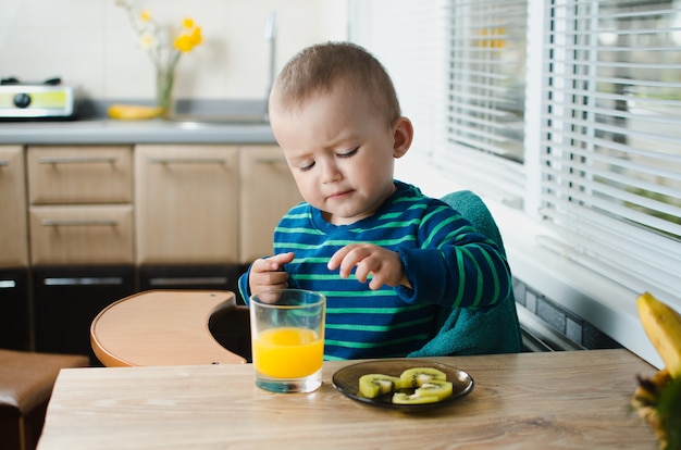 Het kind in de keuken met het sinaasappelsap en de kiwi, gezond, schattig en mooi