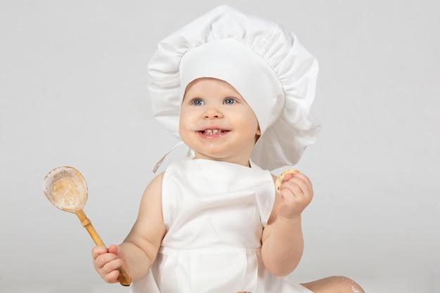 Het kind is een jaar oud grappige baby lacht kleine chef-kok het concept van het koken van voedsel