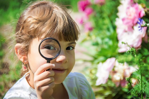 Het kind kijkt in een vergrootglas. Toenemen. selectieve aandacht.